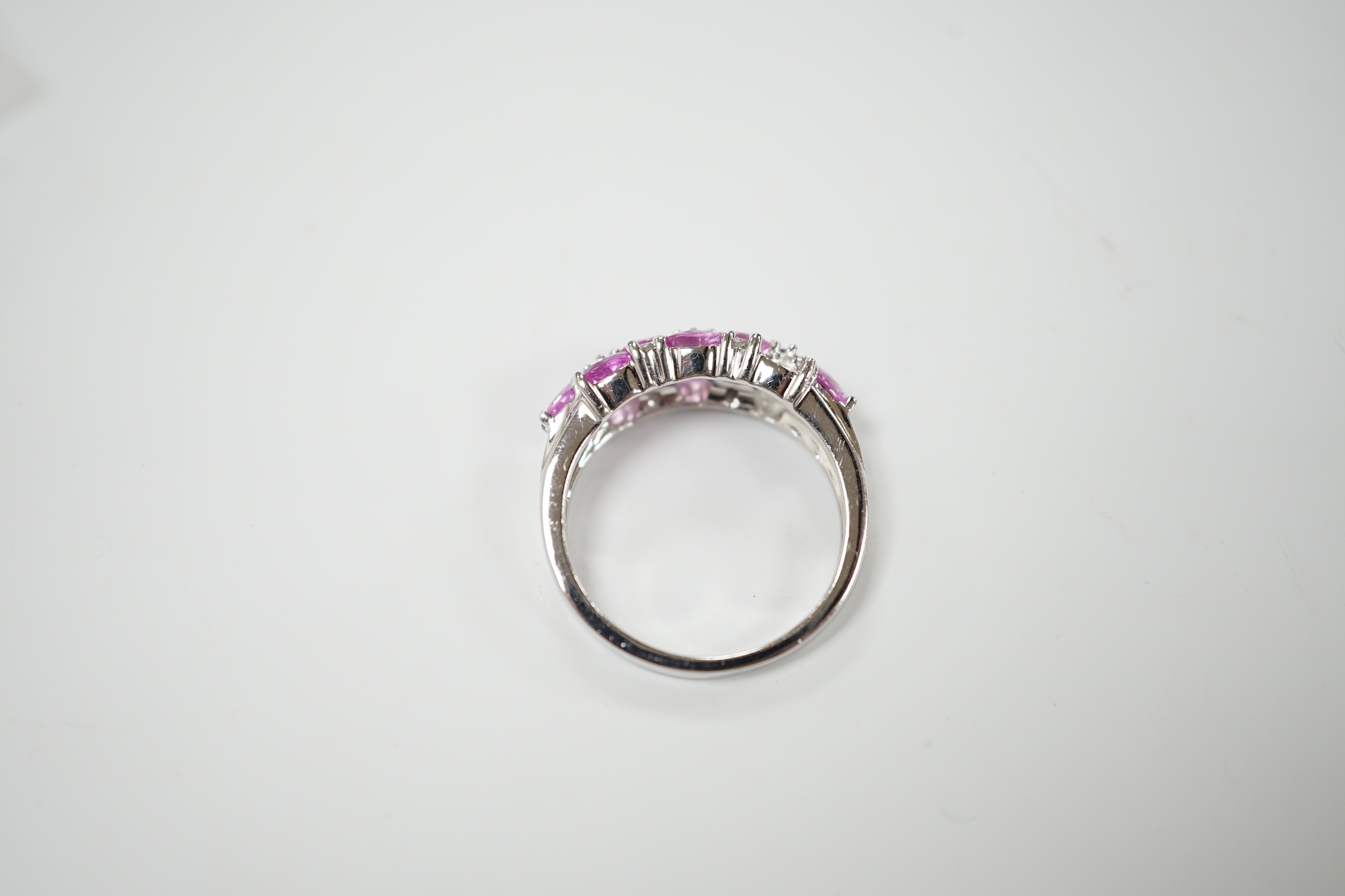 A modern 14k white metal, pink sapphire and diamond cluster set half hoop ring (two sapphires loose), size O, gross weight 4.7 grams.